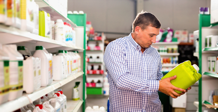 Man choosing liquid fertilizer in plastic bottle in hypermarket
